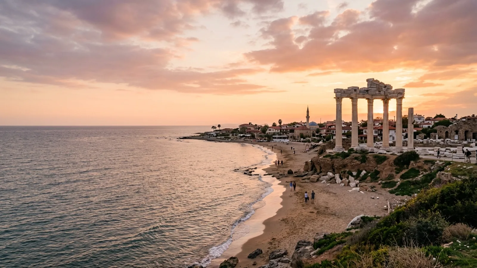 Side, Türkiye — the ancient seaside town of Side, standing marble columns of a Roman temple on a low headland above a sandy beach at sunset.