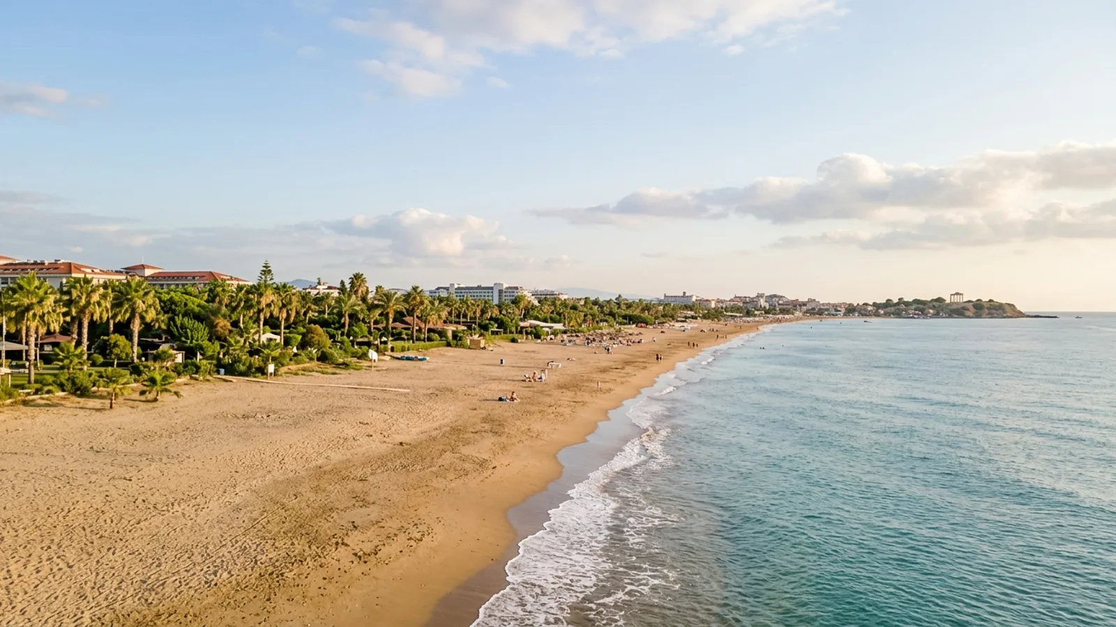 Colakli, Türkiye — the long sandy beach at Colakli near Side, shallow turquoise water and a flat coastal plain of hotel gardens and palms behind.