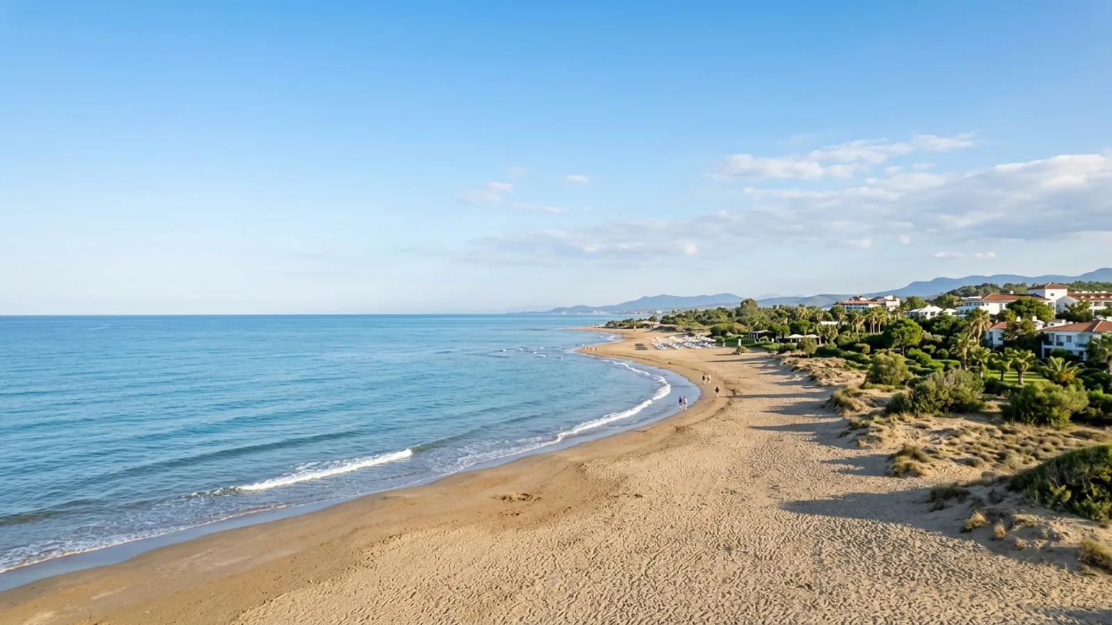 Evrenseki, Türkiye — the sandy coastline at Evrenseki near Side, a gently shelving beach with low dunes and resort gardens set back from the shore.