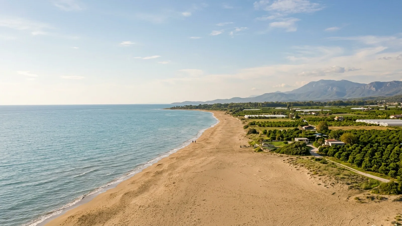 Gundogdu, Türkiye — the quiet sandy shore at Gundogdu on the coast east of Side, a flat farmed plain of orchards behind the beach.