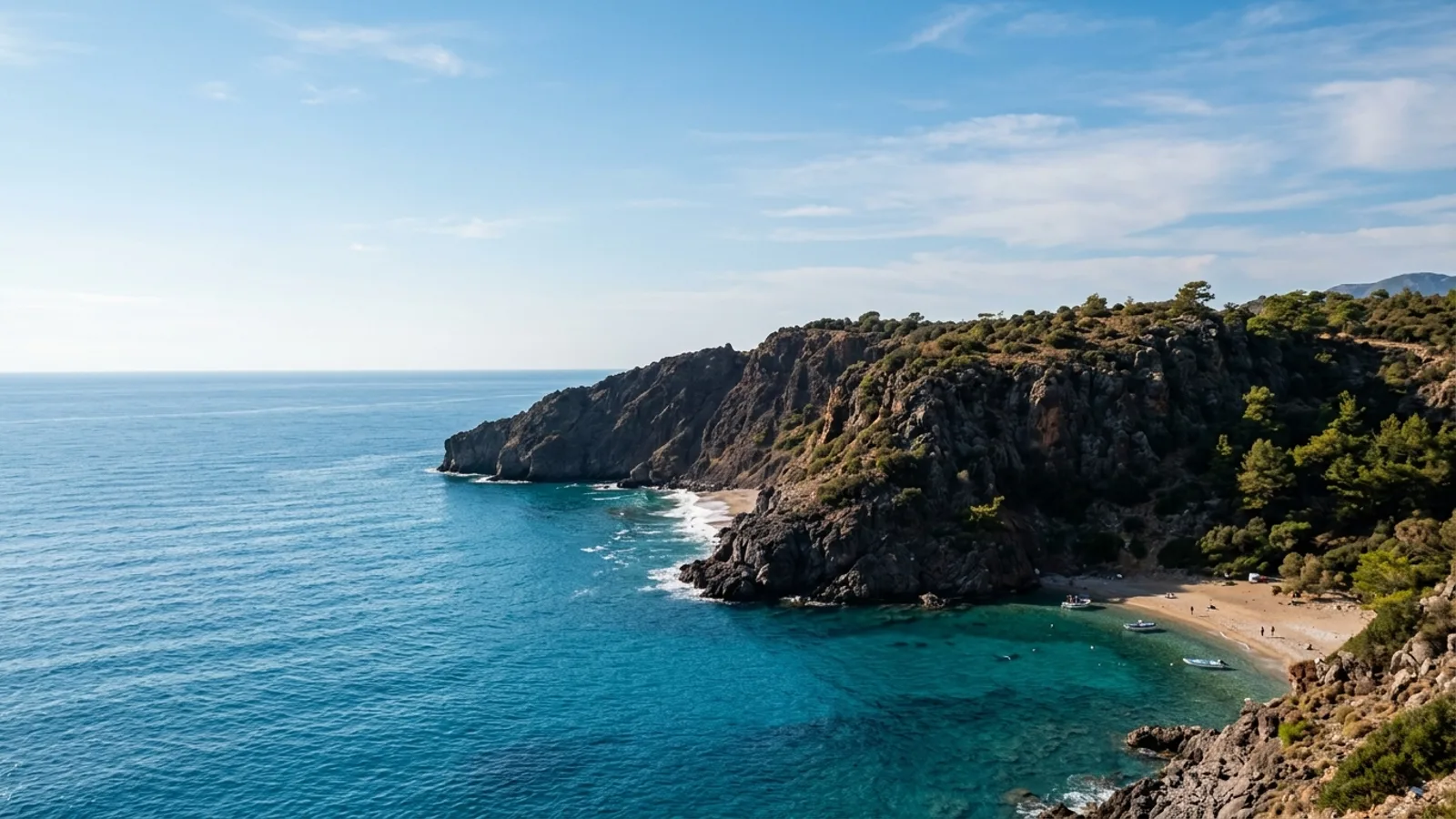 Karaburun, Türkiye — the rocky headland at Karaburun on the Antalya coast, dark cliffs meeting clear blue water with a small beach in the shelter of the point.