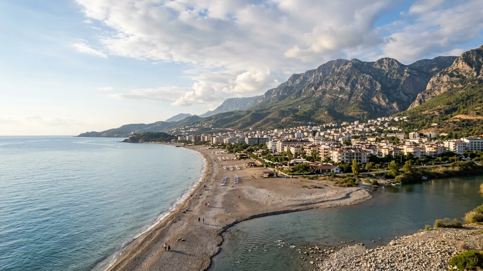 Tosmur, Türkiye — the Tosmur district east of Alanya, a pebble beach and a river mouth with the Taurus mountains rising steeply behind the town.